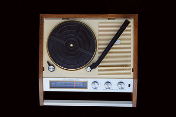Old radio-phonograph. Turntable platter, tonearm, AM radio dial, buttons, and switches. The...
