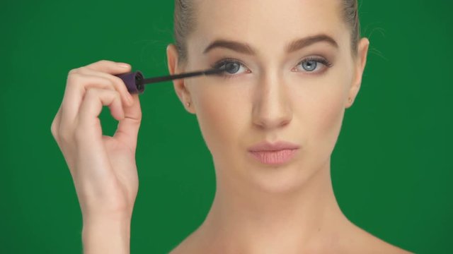 Girl applies mascara on the eyelashes with a makeup brush