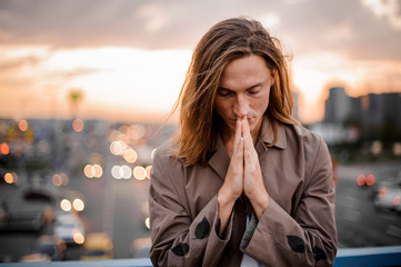 Attractive redhead young man with closed eyes on the background of city