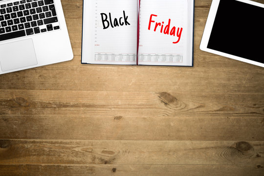 Black Friday. Marked a super sale day in the calendar next to the computer and tablet on a wooden table.