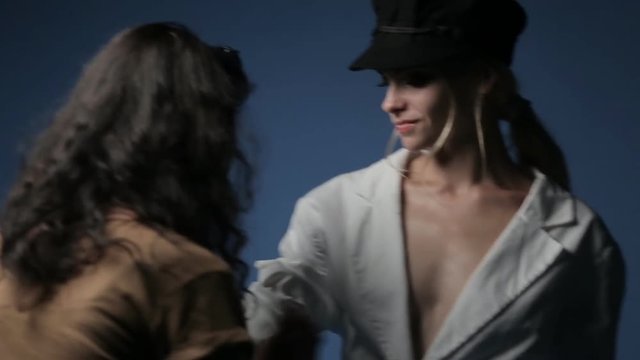 A make-up artist and a stylist work with a model in a black hat
