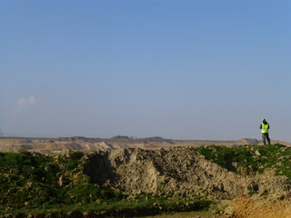 Construction worker in front of a huge coal mining area