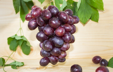 grapes on a brown background. a bunch of grapes. grapes, green leaves. dark blue grapes.