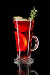 Glass of hot fruit tea with reflection on black background