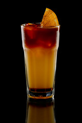 Cocktail with rum and orange juice with ice and lime in oldfashioned glass with reflection