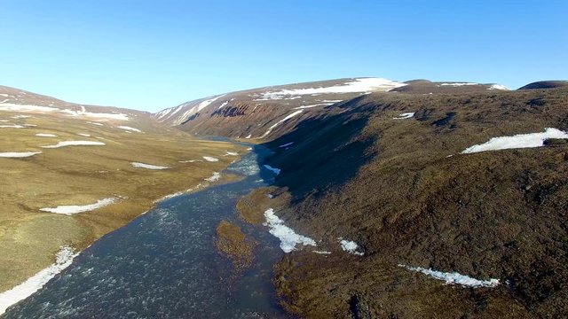 Still aerial shot over a river flowing through the arctic mountains