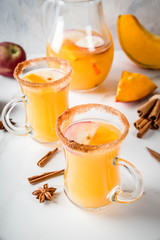 Halloween, Thanksgiving. Traditional autumn, winter drinks and cocktails. Spicy hot pumpkin sangria, with apple, cinnamon, anise. On a white marble table, in glass mugs. Selective focus, copy space