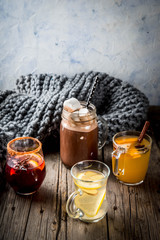 Selection of various autumn traditional drinks: hot chocolate with marshmallow, tea with lemon and ginger, white pumpkin spicy sangria, mulled wine. On wooden rustic table, copy space, selective focus