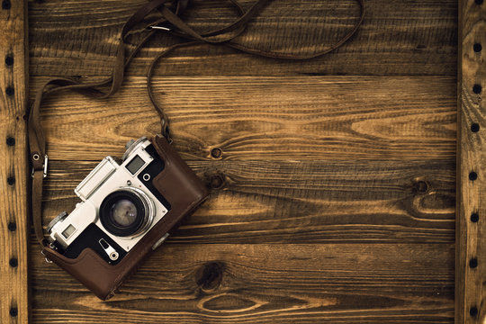 Old retro camera on vintage rustic wooden planks boards. Education photography courses back to  school concept abstract background. Close up, top view, copy space.
