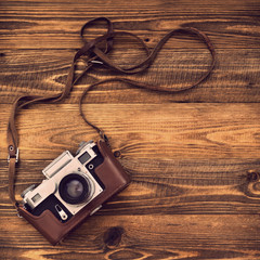 Old retro camera on vintage rustic wooden planks boards. Education photography courses back to  school concept abstract background. Close up, top view, copy space. - obrazy, fototapety, plakaty