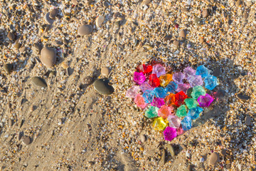 Brightly colored heart of glass pebbles on the sea shore