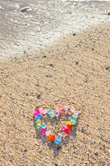 Brightly colored heart of glass pebbles on the sea shore