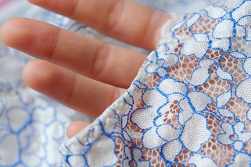 Beautiful delicate openwork white and blue lace in hand  - obrazy, fototapety, plakaty