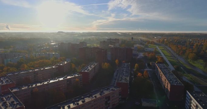 Beautiful Aerial Shot of Misty Sunrise in small town. Colorful clouds, fog above the city. Autumn landscape. 