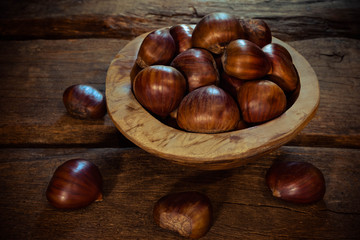 fresh chestnuts in a bowl on wooden background