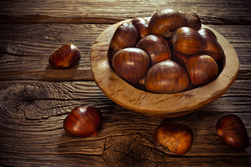 fresh chestnuts in a bowl on wooden background