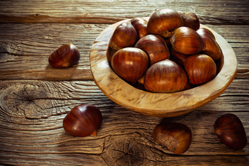 fresh chestnuts in a bowl on wooden background