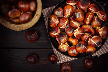 Obraz premium chestnuts in a pan on dark wooden background