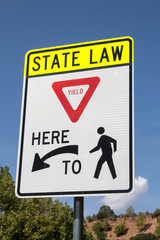 Sign as a reminder of state law for pedestrian crossing