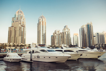 Fototapeta na wymiar Luxury yachts parked on the pier in Dubai Marina bay with city view