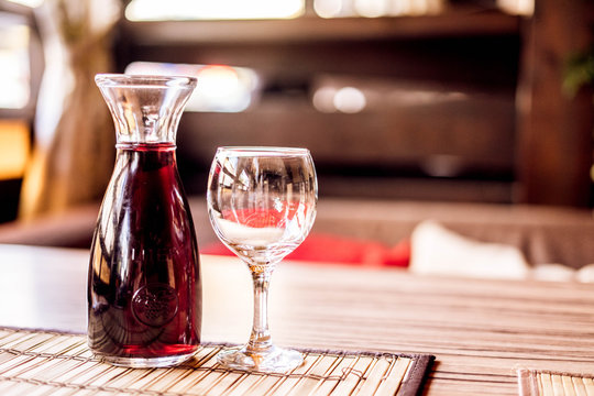 A decanter with red wine and a glass of red wine in a cafe on wooden table. Serving on the table.