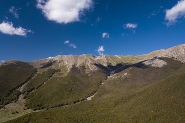 Aerial view of a beautiful mountain landscape, with hills full of green trees and a  small valley. Autumn season in Italy.