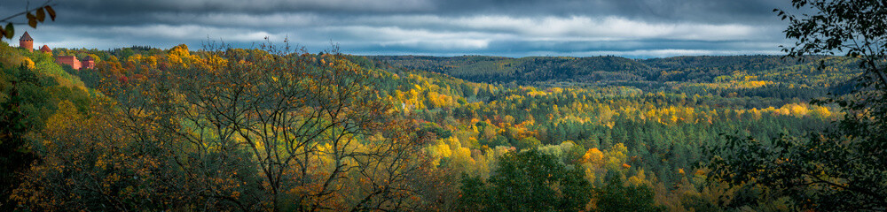  Picturesque view on valley of Gaujas national park. Trees changing colors in foothills.  Colorful Autumn day at city Sigulda in Latvia. 