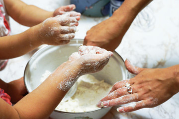 Mother and kids hands making dough on the table