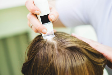 Hair doctor checking hair. Diagnostics hair and scalp.Trihoskopiya. Doctor examine patient female hair a special apparatus