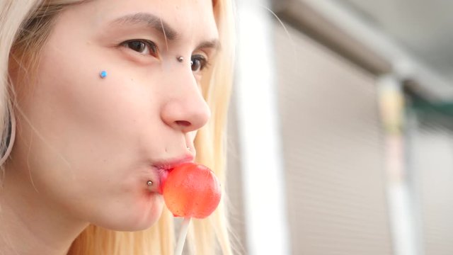 bodymification. a girl with a split tongue licks lollipop. 4k, slow-motion shooting, copying space