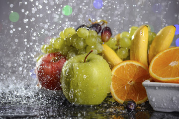 Fototapeta na wymiar Festive still-life from fresh colorful fruits in drops and splashes of falling water 