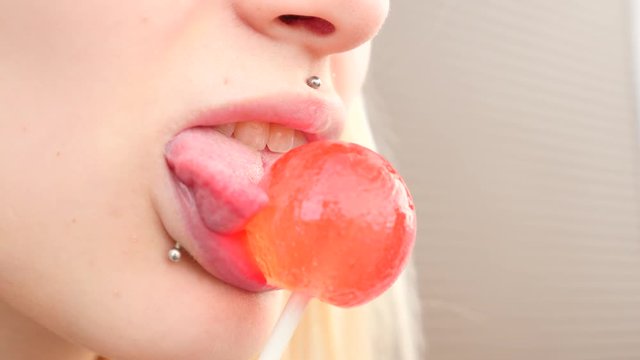 bodymification. a girl with a split tongue licks lollipop. 4k, slow-motion shooting, copying space