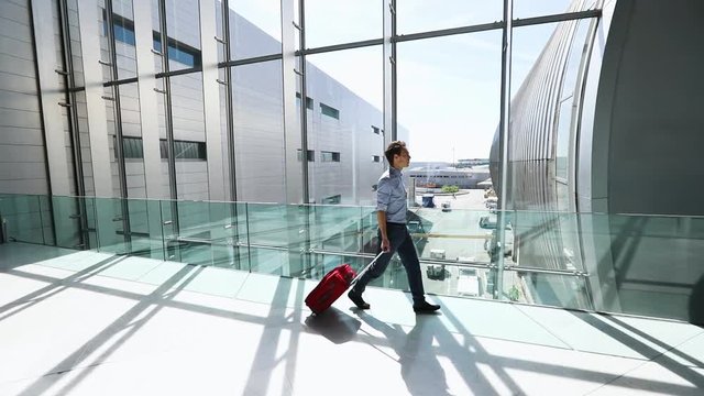 Businessman walking with a suitcase in airport terminal to go to the boarding gate, business travel, flight