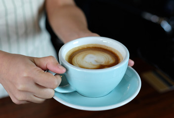 Woman hands holding green coffee cup at cafe background, close up, food and drinks concept