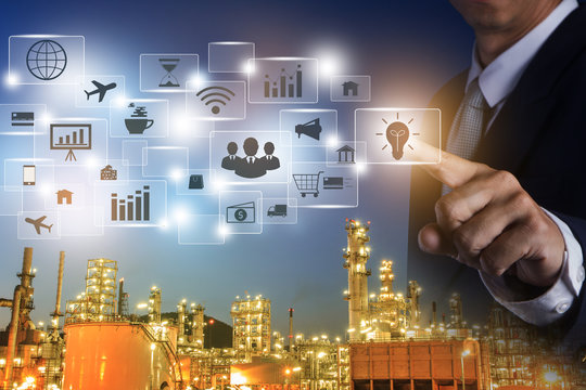 Business man working with modern virtual technology and pressing Big data analytics and business intelligence (BI). Businessman Pressing Virtual icons with Oil refinery double exposure. - Powered by Adobe