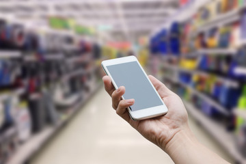 hand holding mobile smart phone with blank monitor screen on Supermarket blur background, business concept
