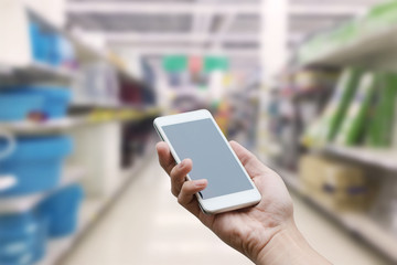 hand holding mobile smart phone with blank monitor screen on Supermarket blur background, business concept