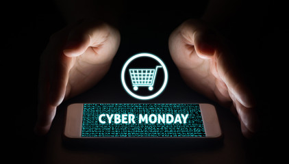 Cyber monday. Man hands holding smart phone with cyber monday text and cart on virtual screens on smartphone.