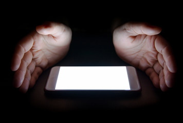 white light from the smartphone reflect your hand at night in the dark.blank screen for text and design