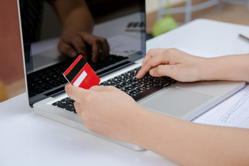 woman useing laptop and holding credit card with online shopping or internet banking online.