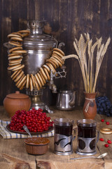 Russian traditional kettle samovar on the wooden table. Black tea, bagels, red viburnum, jam and russian samovar in the rustic style.