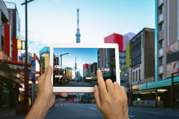 Hand holding tablet use AR application to check relevant information. Japan City in marketing...