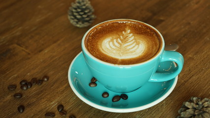 Hot coffee latte mocha espresso cappuccino with heart shape foam in green cup coffee shop wooden tabvle and coffee bean