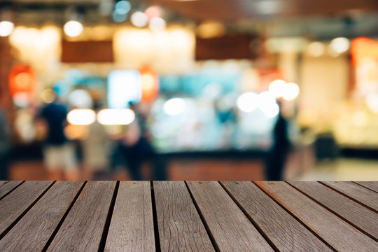 blur image wood table on shopping mall and people with bokeh.