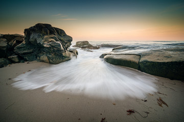 A wave bursts through the rocks along the San Diego, California coastline