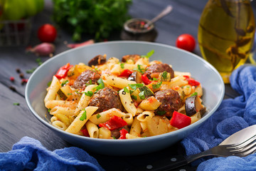 Penne pasta with meatballs in tomato sauce and vegetables in bowl