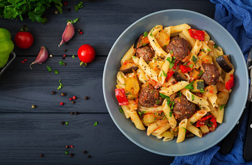 Penne pasta with meatballs in tomato sauce and vegetables in bowl