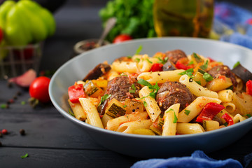 Penne pasta with meatballs in tomato sauce and vegetables in bowl