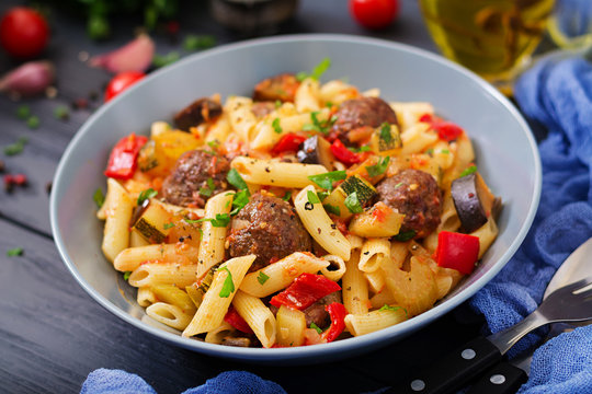 Penne pasta with meatballs in tomato sauce and vegetables in bowl