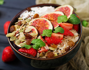 Delicious and healthy oatmeal with figs, seeds, strawberry and yogurt. Healthy breakfast. Fitness food. Proper nutrition.